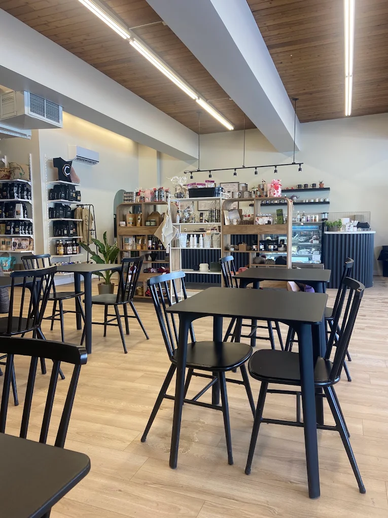 La salle du Café-in : tables noires, plancher de chêne clair et, au fond, les étagères de la boutique de produits locaux