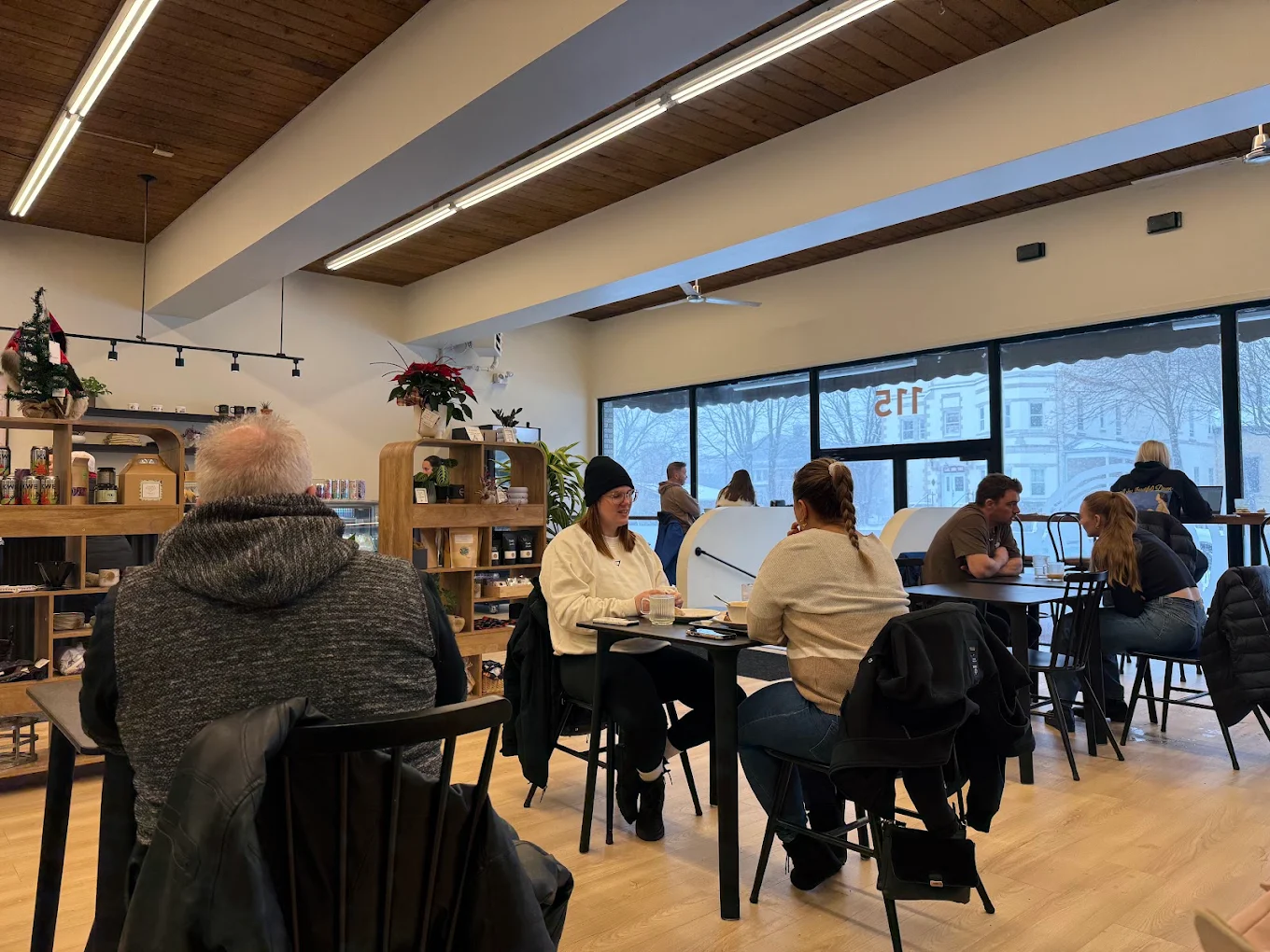 La salle du Café-in animée par un jour d'hiver, clients attablés devant les grandes vitrines